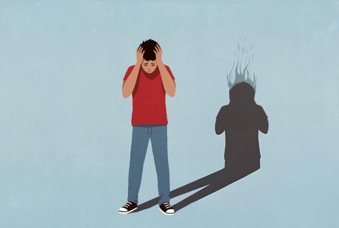 Person që mban kokën me duar, duke treguar dhimbje të forta të kokës nga tensioni ose migrena.